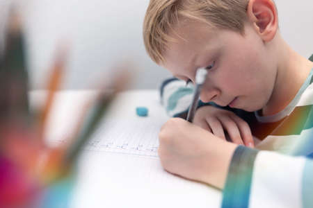 School boy practicing writing the alphabet at home. Boy child kid writing. Homework.の写真素材
