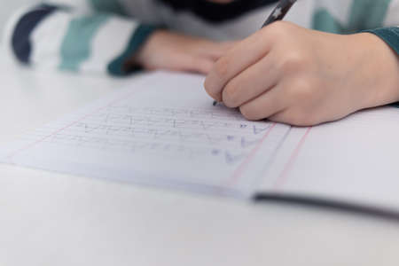 School boy practicing writing the alphabet at home. Boy child kid writing. Homework.