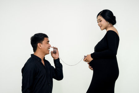 Sweet young husband talking to her baby from the mother's belly. communication with baby conceptの写真素材