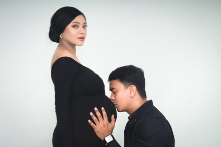 Sweet young husband talking to her baby from the mother's belly. communication with baby conceptの写真素材