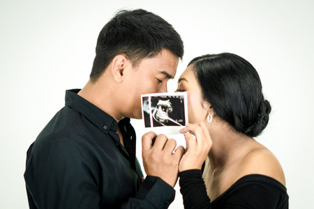 Young couple shows ultrasound image of their baby, focus on ultrasound imageの写真素材