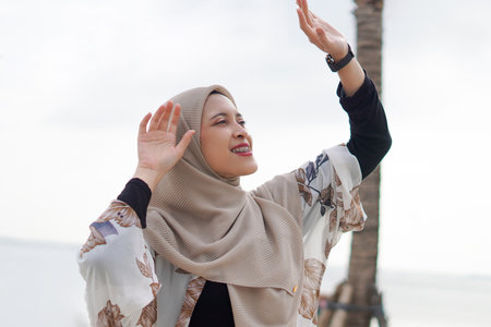 Pretty muslim woman enjoying sun shine at the beach wearing cardigan.の写真素材