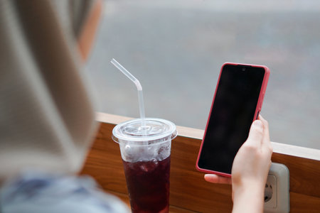 Modern Muslimah woman. Indonesian Woman in Hijab Embracing Digital Connectivity with Smartphoneの写真素材