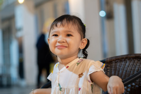 Cute lil' girl sitting on wooden chair and smilingの写真素材
