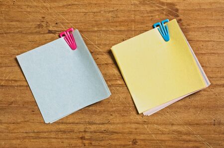 Two Post it with plastic clip on wooden board.
