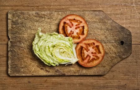 Cut tomatoes and lettuce on cutting table.の写真素材