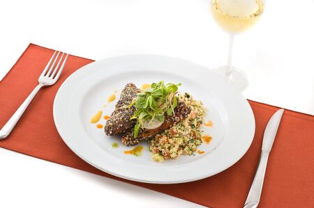 Gourmet salmon dish garnished with vegetables, white background.の写真素材