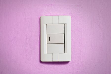 White light switch on old pink wall.の写真素材