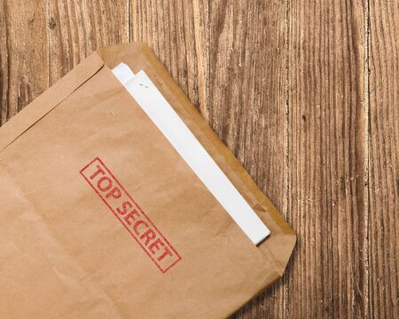 Open yellow envelope with top secret stamp and papers, on wooden tableの写真素材