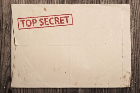 Open yellow envelope with top secret stamp and papers, on wooden tableの写真素材