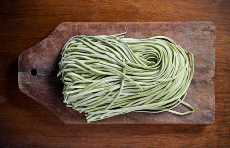 Green pasta on wooden table.