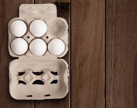 Eggs in a box on wooden table.