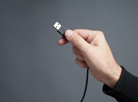 Hand holding black USB cableの写真素材