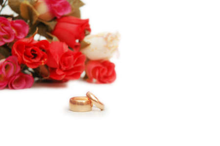 Two wedding rings and flowers at the backgroundの写真素材