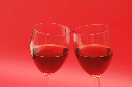 Two wine glasses against the red backgroundの写真素材