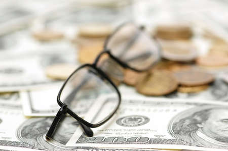 Reading glasses with coins  and dollar bank notesの写真素材