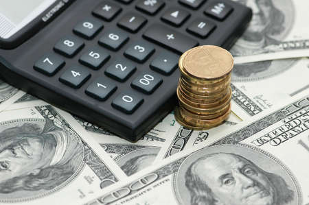 Calculator and  stack of coins over dollar bank notesの写真素材