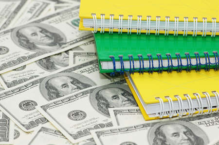 Three spiral notebooks and us  dollar background