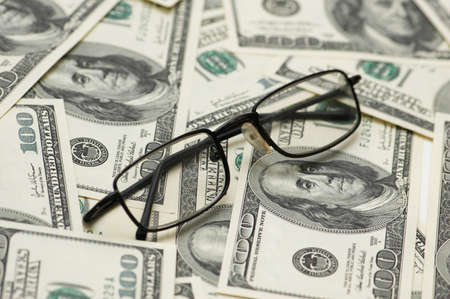 Reading glasses over  hundred dollar bank notesの写真素材
