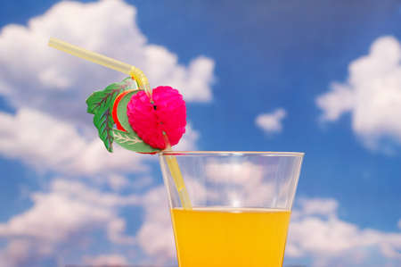 Orange juice with straw against  cloudy skyの写真素材