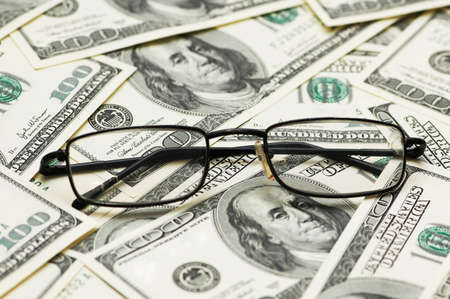 Reading glasses over the dollar bank notesの写真素材