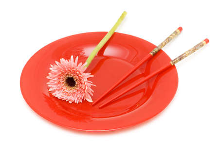 Red flower and plate with chopsticks isolated on whiteの写真素材