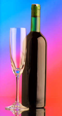 Bottle of wine and glass against colour backgroundの写真素材