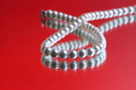 Pearl necklace on the red reflective backgroundの写真素材