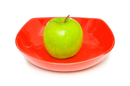 Green apple in the red plate on whiteの写真素材