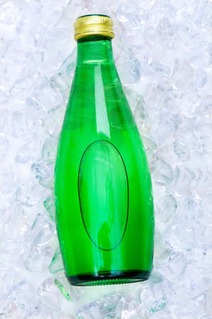 Green bottle of water on ice cubesの写真素材