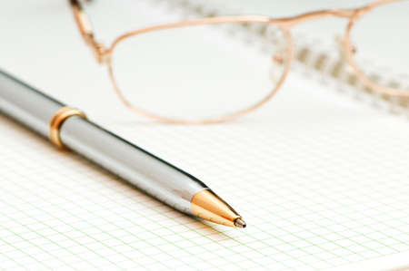 Pen and eye glasses on the pageの写真素材