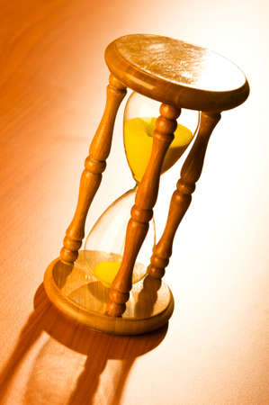 Time concept with hourglass on wooden background