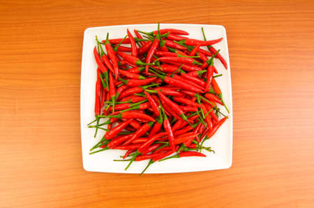 Hot peppers in the plate on wooden table