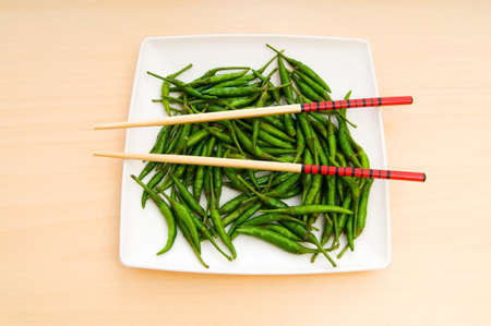 Hot peppers with chopsticks and plateの写真素材