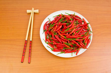 Hot peppers with chopsticks and plateの写真素材
