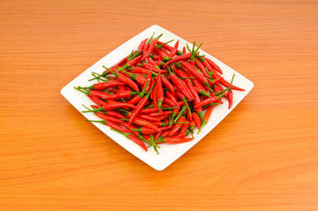 Hot peppers in the plate on wooden table