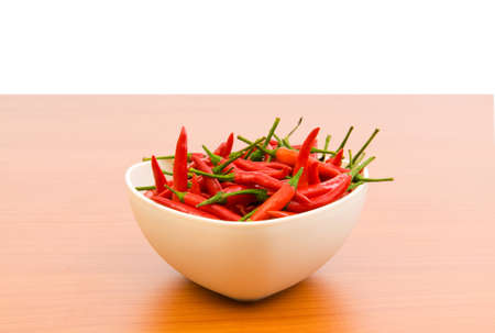 Hot peppers in the plate on wooden table