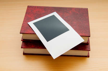 Books and blank photos on wooden tableの写真素材