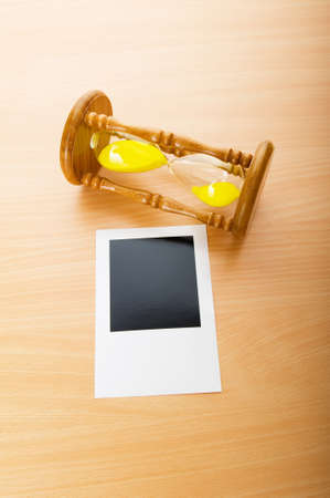 Blank instant photos and hour glass on the wooden table