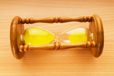 Time concept - hourglass against the wooden background