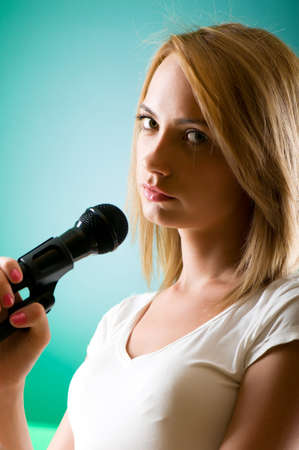 Girl singing with microphone against gradient backgroundの写真素材