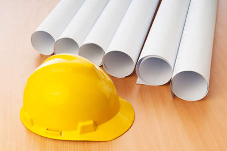 Drawings and hard hat on the deskの写真素材