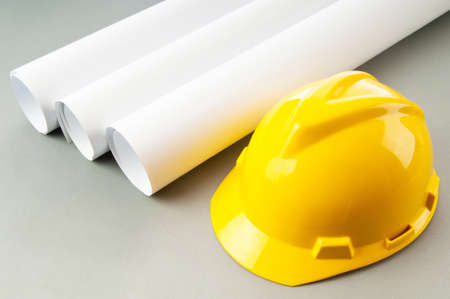 Drawings and hard hat on the deskの写真素材