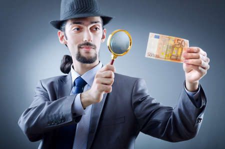 Detective looking at fake moneyの写真素材