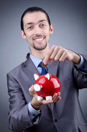 Man with piggybank on greyの写真素材