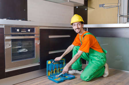 Repairman assembling the furniture at kitchenの写真素材