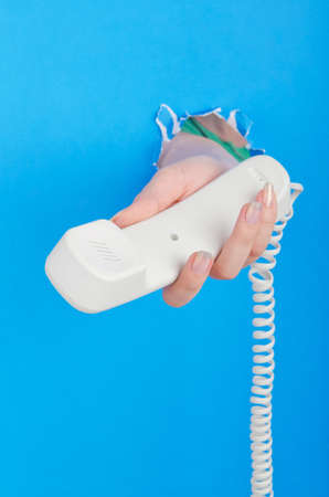 Hand with phone out of paper holeの写真素材