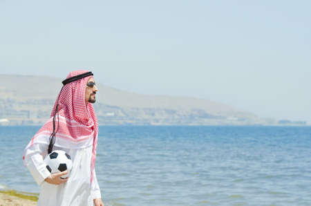 Arab with footbal at seasideの写真素材