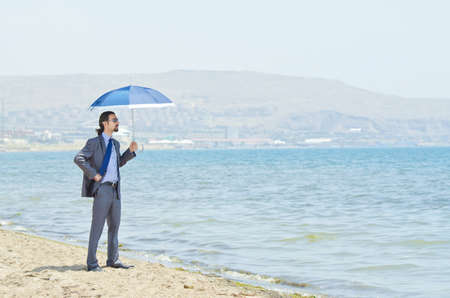 Man with umbrella on seaside beachの写真素材