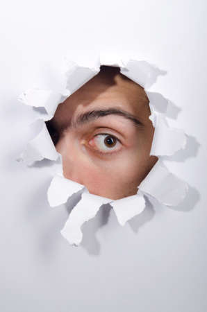 Male face through the hole in paperの写真素材